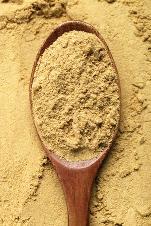 Heap of aromatic mustard powder and wooden spoon, top viewの写真素材