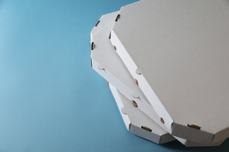 Stack of empty pizza boxes on light blue background, closeup. Space for textの写真素材