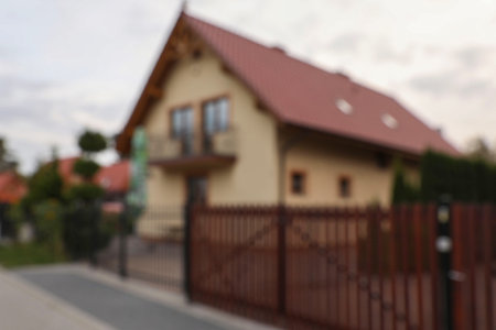 Beautiful house near fence outdoors, blurred view. Real estate for rentの写真素材