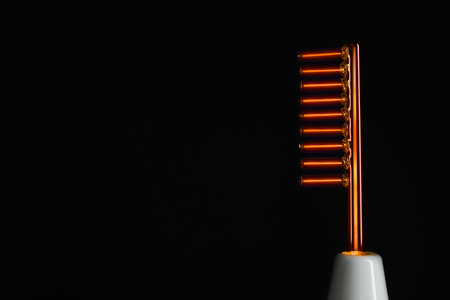 Working high frequency personal device on black background, closeup. Space for text