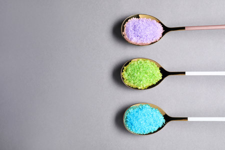 Spoons with colorful sea salt on light grey table, flat lay. Space for textの写真素材