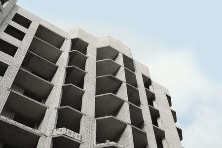 Construction site with unfinished building under cloudy sky, low angle viewの写真素材