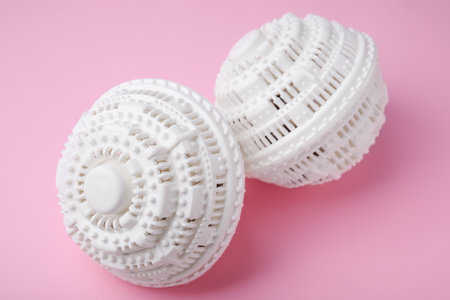 Dryer balls for washing machine on pink background, closeup. Laundry detergent substitute