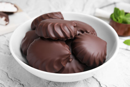 Delicious chocolate covered zephyrs in bowl on light grey table, closeupの写真素材