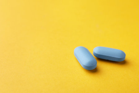 Pills on orange background, space for text. Potency problemの写真素材