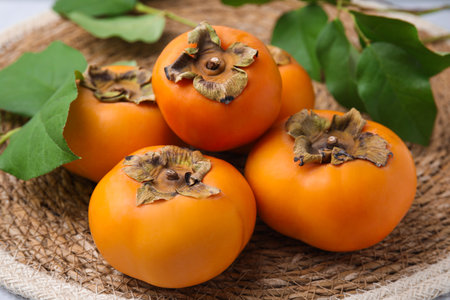 Delicious ripe juicy persimmons on wicker mat, closeupの写真素材