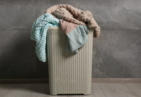 Laundry basket with clothes near gray wallの写真素材