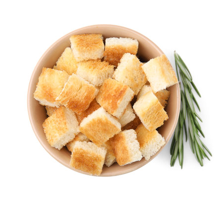 Delicious crispy croutons in bowl and rosemary on white background, top viewの写真素材