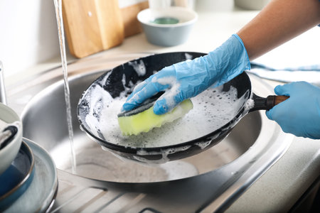 Woman washing dirty frying pan in sink indoors, closeupの写真素材