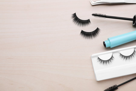Flat lay composition with false eyelashes and tools on wooden table. Space for textの写真素材