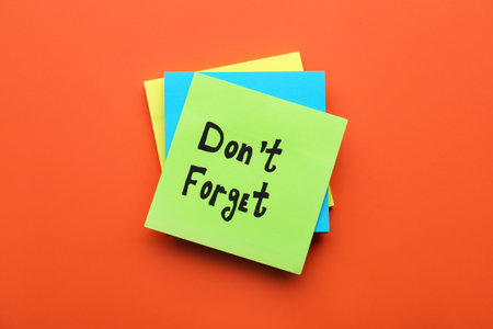 Paper note with phrase Don't Forget on orange background, top viewの写真素材