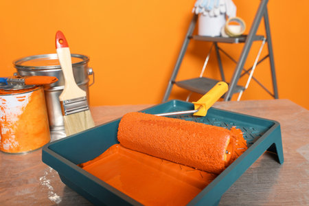 Tray with orange paint and roller on table, closeupの写真素材