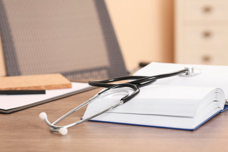 Book and stethoscope on wooden table indoors, space for text. doctor educationの写真素材