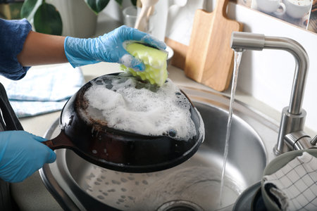 Woman washing dirty frying pan in sink indoors, closeupの写真素材