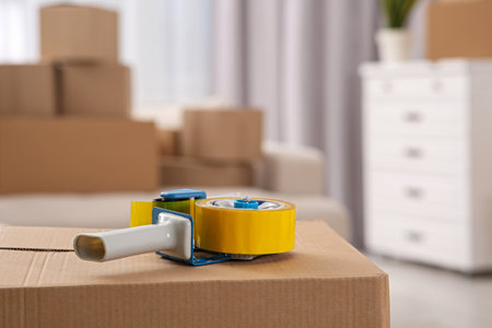 Dispenser with roll of adhesive tape on box indoors. Space for textの写真素材