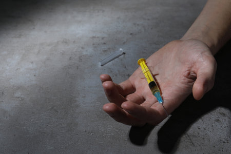 drug addiction. Man with syringe on gray table, closeup and space for textの写真素材