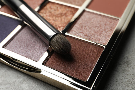 Beautiful eye shadow palette and brush on gray table, closeupの写真素材