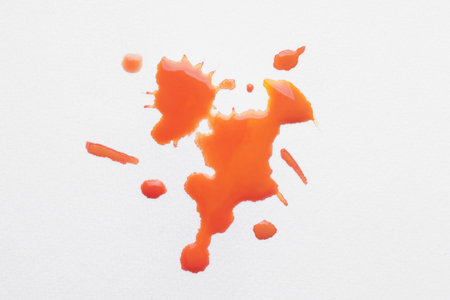 Blot of orange ink on white background, top viewの写真素材
