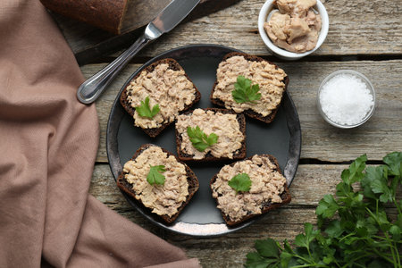 Tasty sandwiches with cod liver, salt and parsley on wooden table, flat layの写真素材
