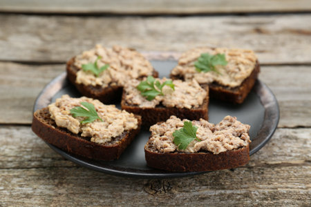Tasty sandwiches with cod liver and parsley on wooden tableの写真素材