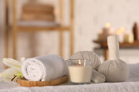 Spa composition with burning candle and herbal bags on massage table in wellness centerの写真素材