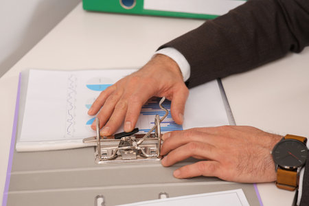 Businessman putting document into file folder at white table in 'office, closeupの写真素材