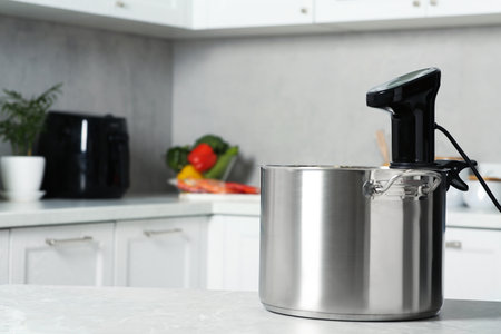 Pot with sous vide cooker on table in kitchen, space for text. Thermal immersion circulatorの写真素材