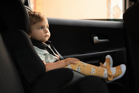 Cute little girl sitting in child safety seat inside carの写真素材