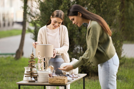 Women shopping at table in yard. Garage sale