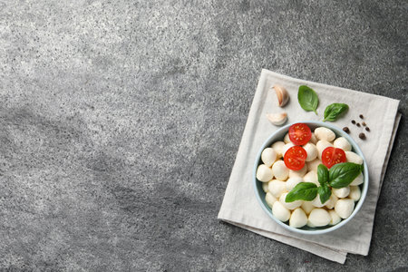Delicious mozzarella balls with tomatoes and basil leaves on light gray textured table, flat lay. Space for textの写真素材