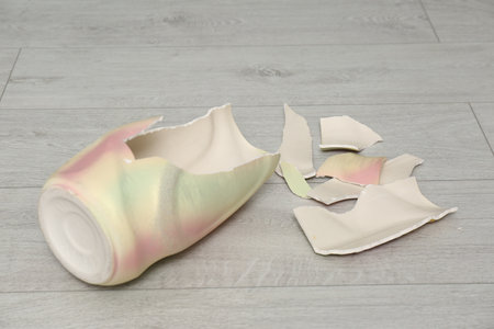 Broken bright ceramic vase on wooden floorの写真素材