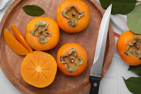 Delicious ripe persimmons and knife on white table, flat layの写真素材