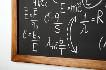 Blackboard with different physical formulas written with chalk on white wallの写真素材