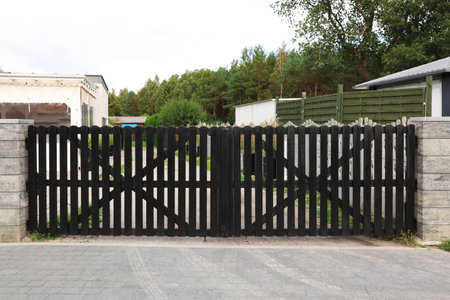 Closed wooden gates near beautiful trees and buildings outdoors