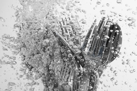 Washing silver cutlery in water on white background, closeupの写真素材