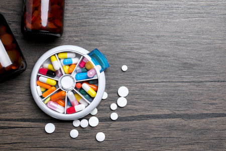 Pill box with medicines on wooden table, flat lay. Space for textの写真素材