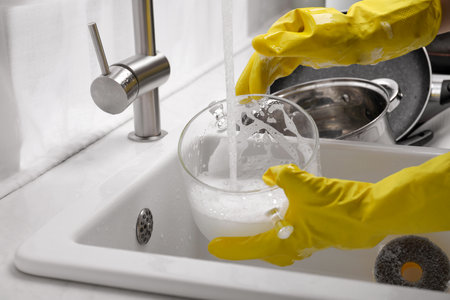 Woman washing glass pot in kitchen sink, closeupの写真素材