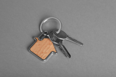 Keys with trinket in shape of house on gray background, above view. real estate agent servicesの写真素材