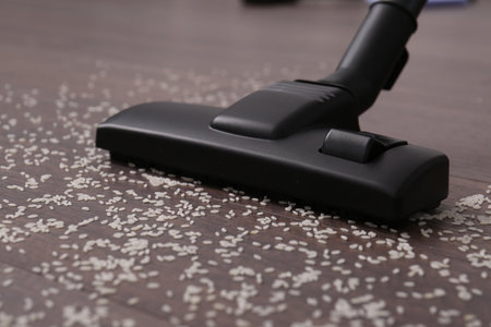 Vacuuming scattered rice from wooden floor, closeupの写真素材