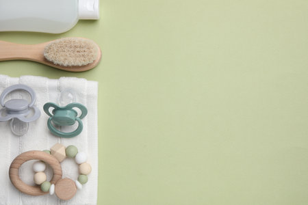 Flat lay composition with pacifiers and other baby stuff on pale green background. Space for textの写真素材