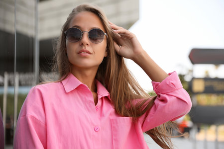 Beautiful young woman in stylish sunglasses on city streetの写真素材