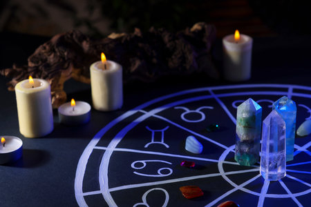 Natural stones for zodiac signs, drawn astrology chart and burning candles on black table. color tone effectの写真素材