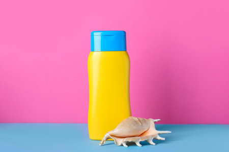 Suntan product and seashell on color backgroundの写真素材