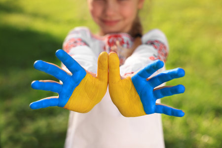 Little girl with hands painted in Ukrainian flag colors outdoors, closeup. love ukraine conceptの写真素材