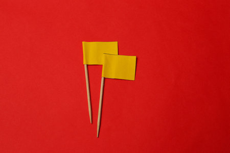 Small yellow paper flags on red background, flat layの写真素材