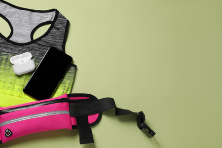 Flat lay composition with stylish pink waist bag on pale green background. Space for textの写真素材