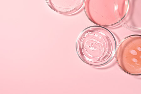 Petri dishes with liquids on pale pink background, flat lay. Space for textの写真素材