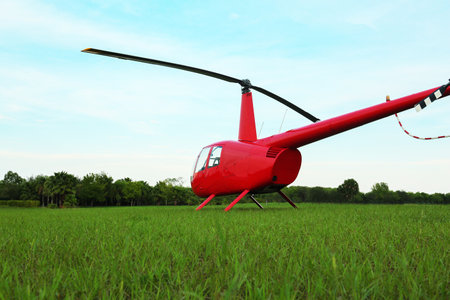 Modern red helicopter on green grass outdoors, low angle viewの写真素材