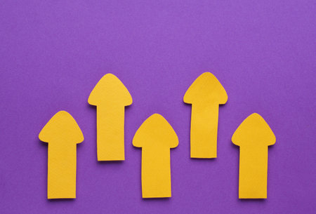 Paper arrows on purple background, flat lay. Space for textの写真素材