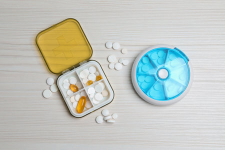 Pill boxes with medicines on white wooden table, flat lay